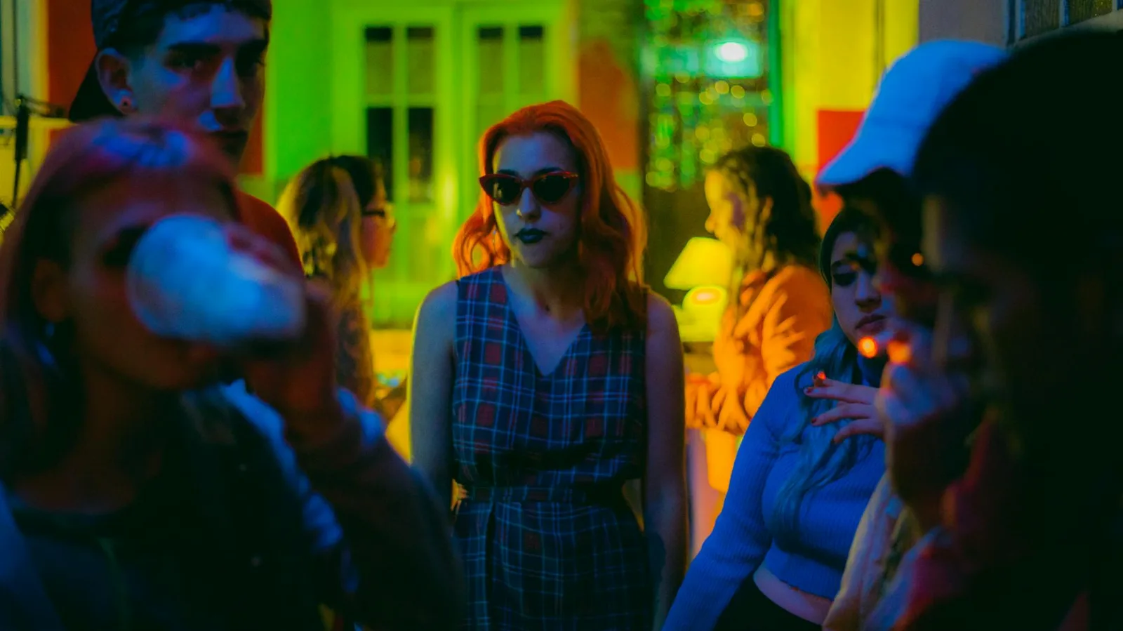 A lively group of people enjoying a vibrant party under colorful neon lights.