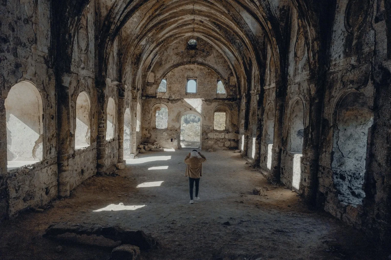 Man explores an abandoned historic church, spotlighting decay and adventure.