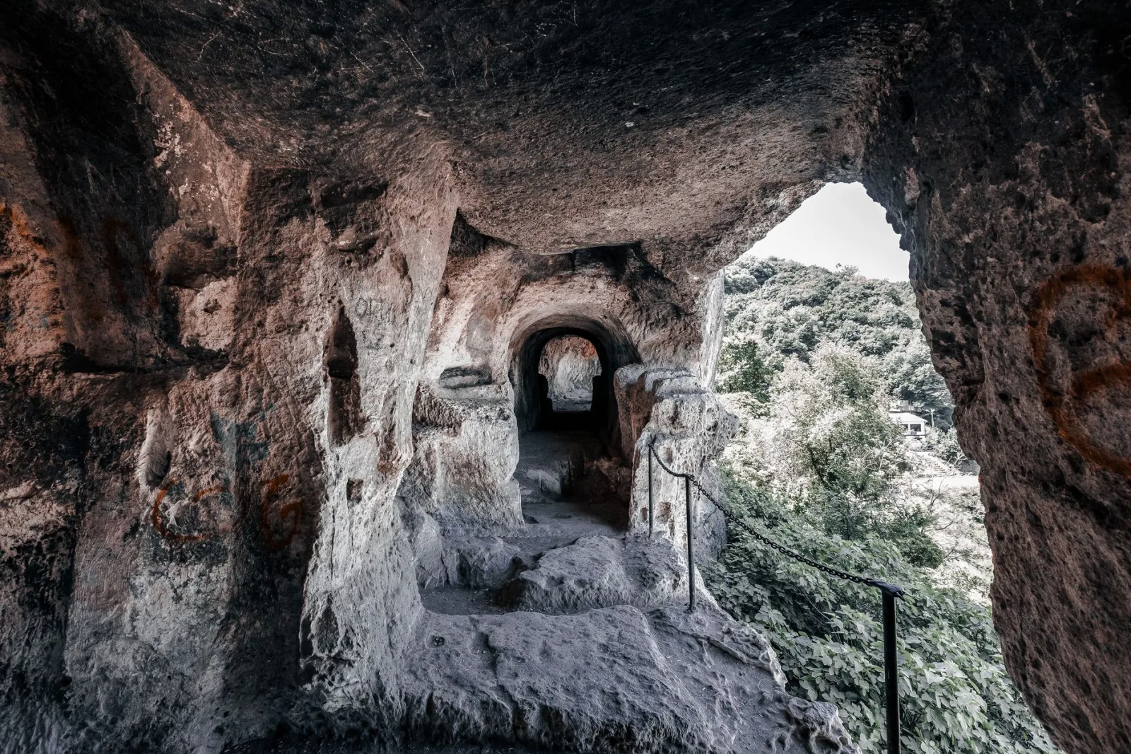 Explore an ancient rock cave passageway leading to nature, capturing a sense of mystery and history.