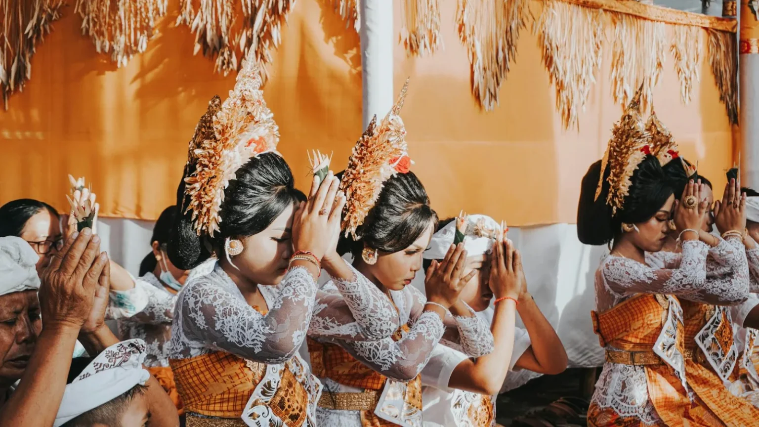 Balinese women in traditional attire participating in a ceremonial Hindu prayer in Bali, Indonesia.