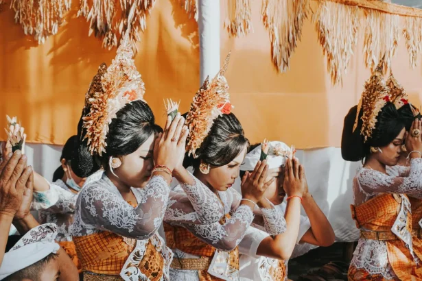 Balinese women in traditional attire participating in a ceremonial Hindu prayer in Bali, Indonesia.