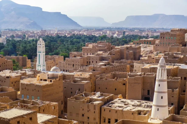 Aerial view showcasing the traditional architecture of a historic town in Yemen with iconic towers and desert landscape.