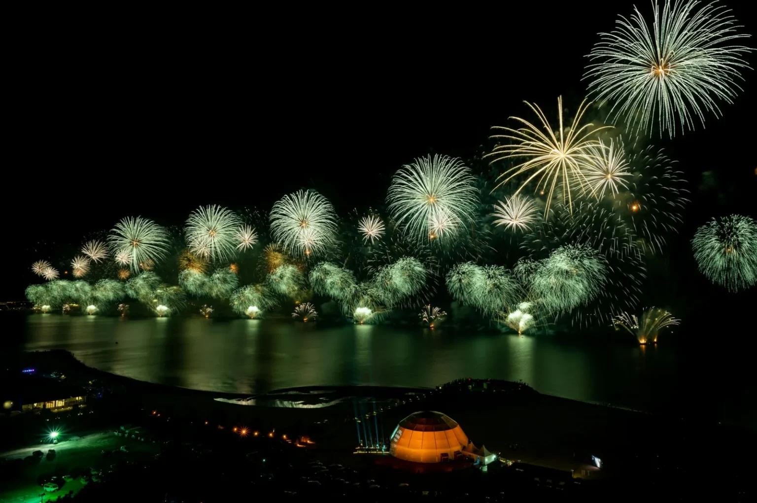 Stunning aerial view of a vibrant fireworks show over the waters of Ras Al Khaimah, UAE, illuminating the night sky.