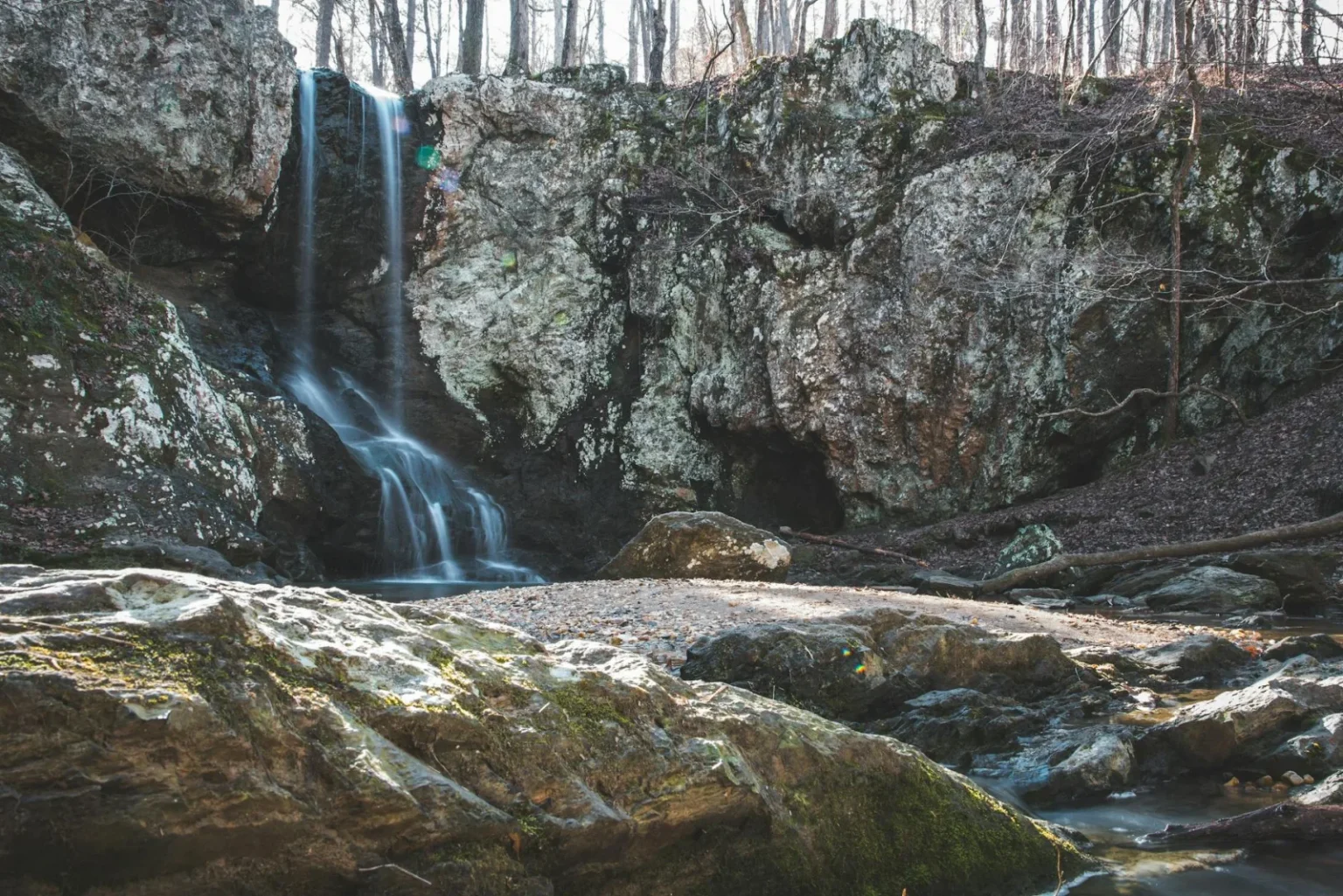A tranquil waterfall cascades down rocky formations in a peaceful forest setting.