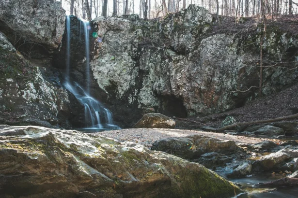 A tranquil waterfall cascades down rocky formations in a peaceful forest setting.