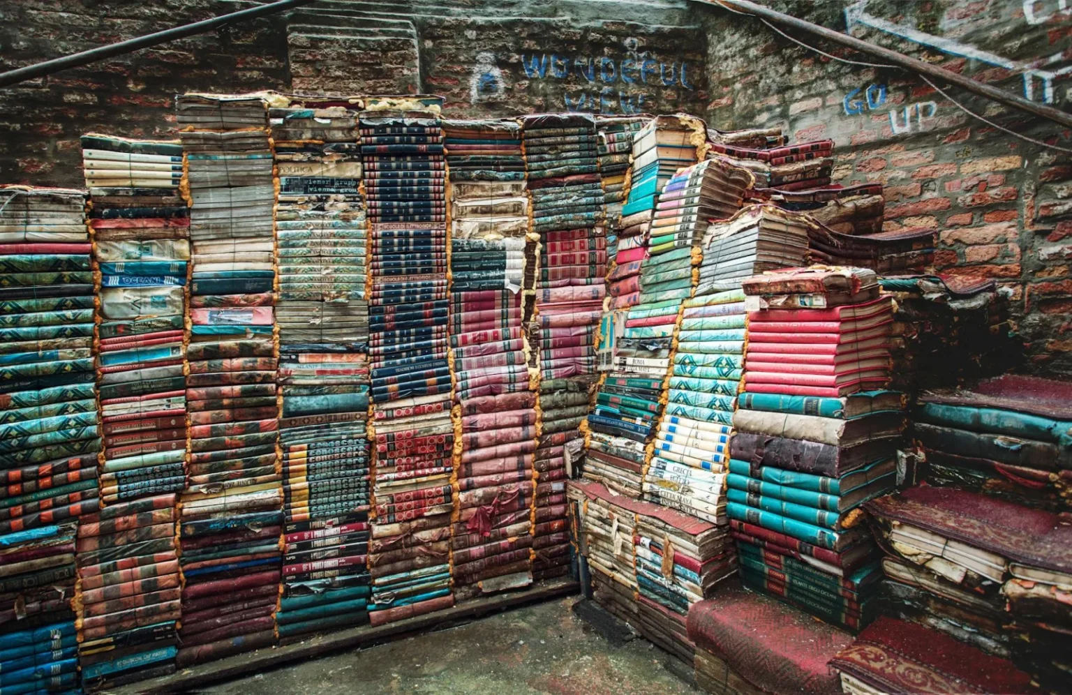 Rustic stacks of colorful books in a charming Venetian alley, creating an artistic display.