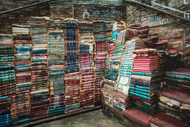 Rustic stacks of colorful books in a charming Venetian alley, creating an artistic display.