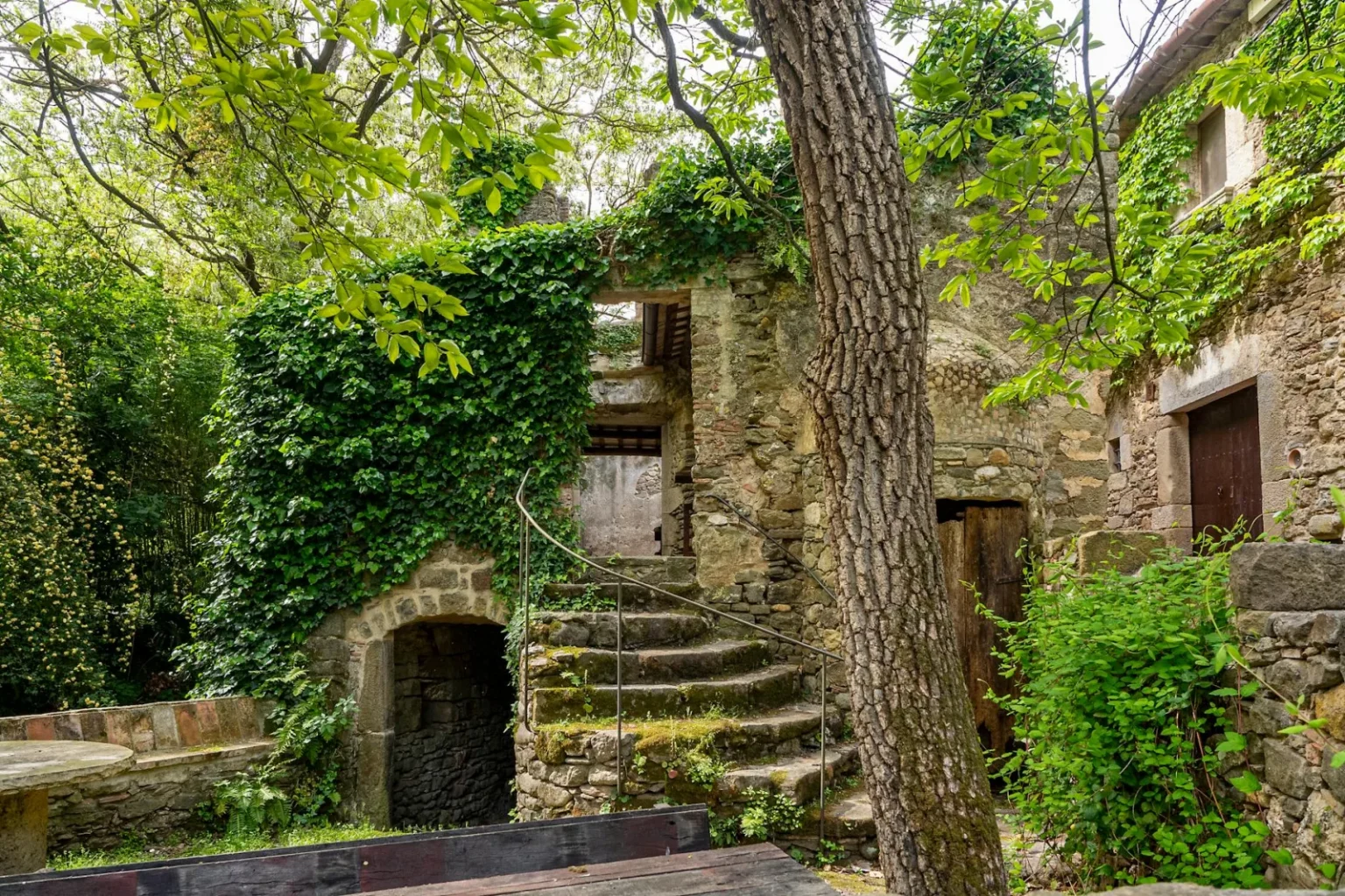 A peaceful scene of an abandoned stone building enveloped by lush greenery.