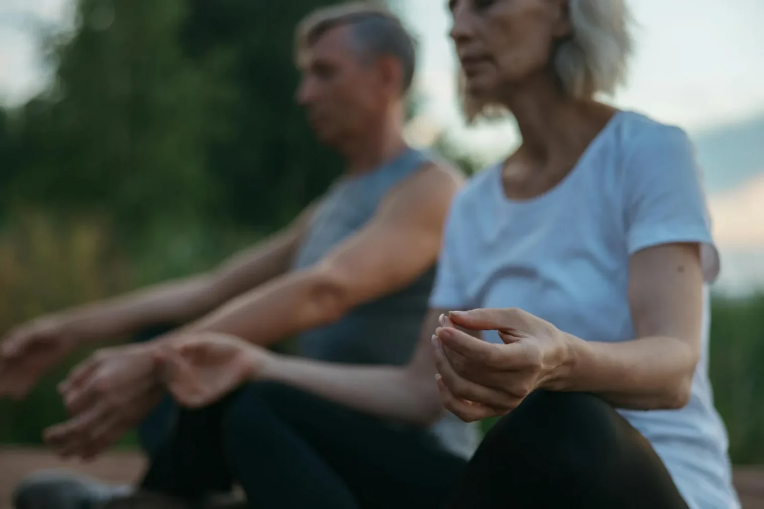 Senior couple practicing meditation outdoors, focusing on mindfulness and tranquility.