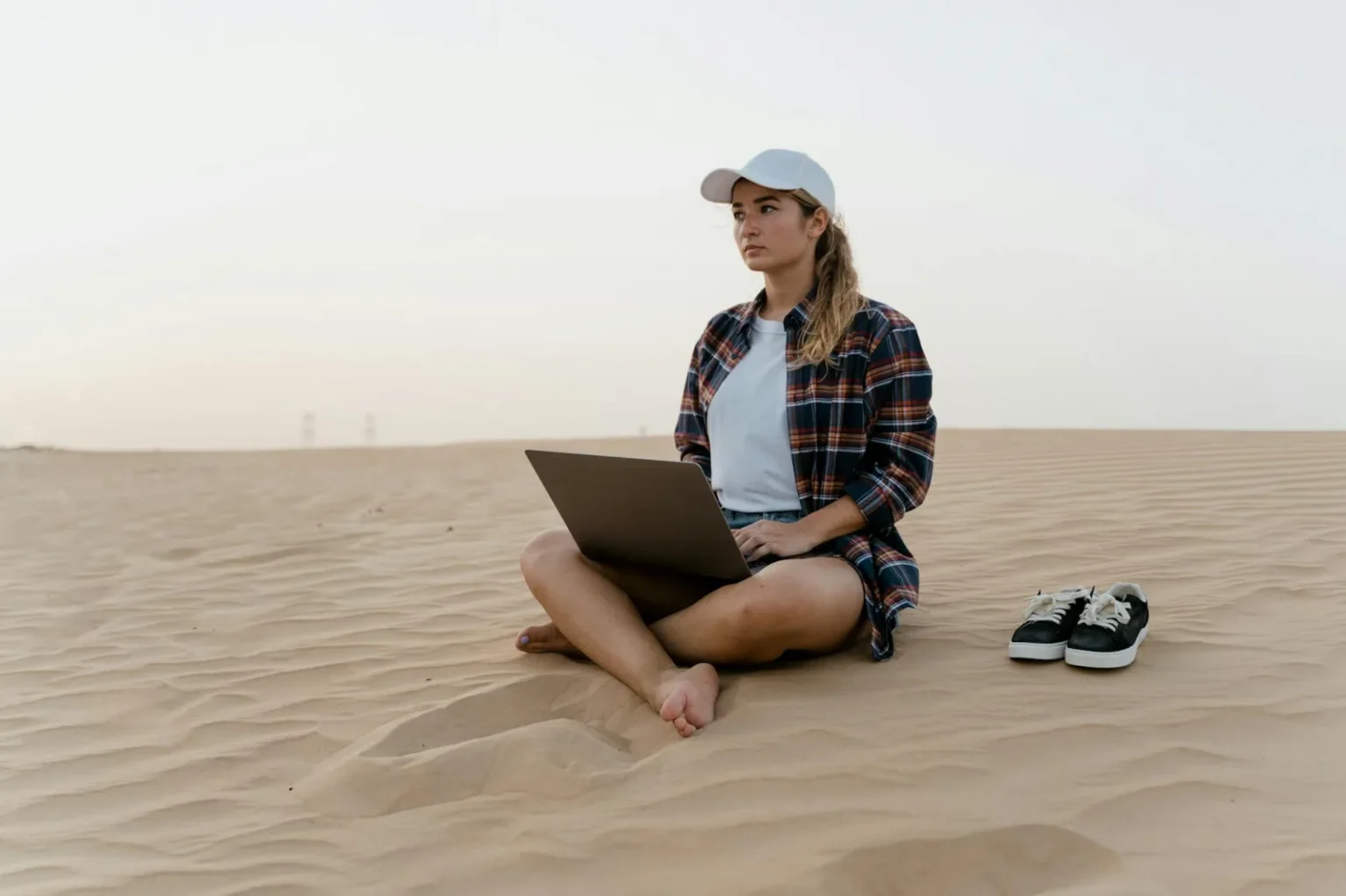A woman working on a laptop in the desert. Ideal for remote work and travel themes.