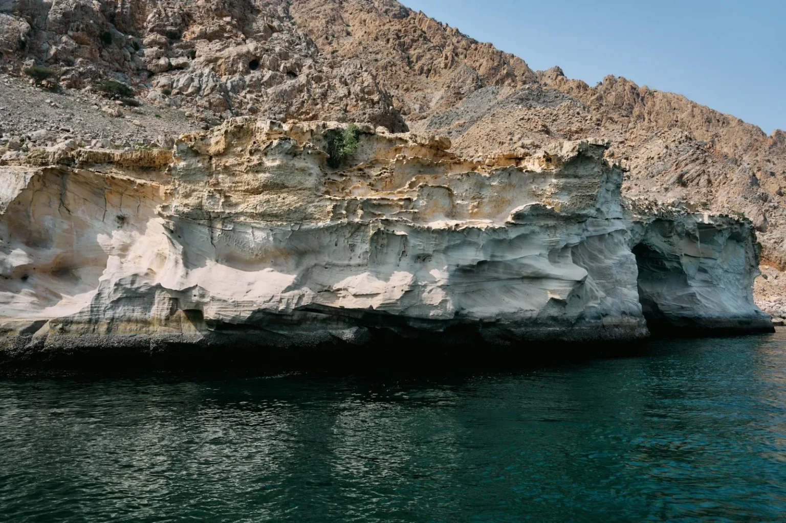 Stunning view of rocky cliffs along the Musandam, Oman coastline during a sunny day.