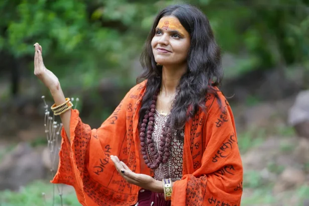 A woman in traditional attire meditating peacefully in a natural setting.