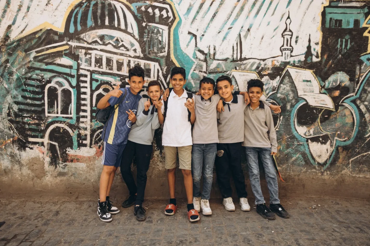 Happy group of boys posing in front of colorful graffiti in Cairo, Egypt.