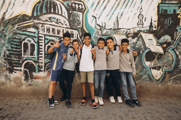 Happy group of boys posing in front of colorful graffiti in Cairo, Egypt.