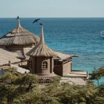 Explore a tranquil coastal resort with unique thatched roofs overlooking the azure sea.