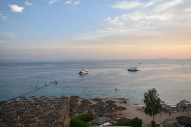 Stunning aerial view of Sharm El Sheikh's beach and sea during sunset with boats and parasols.
