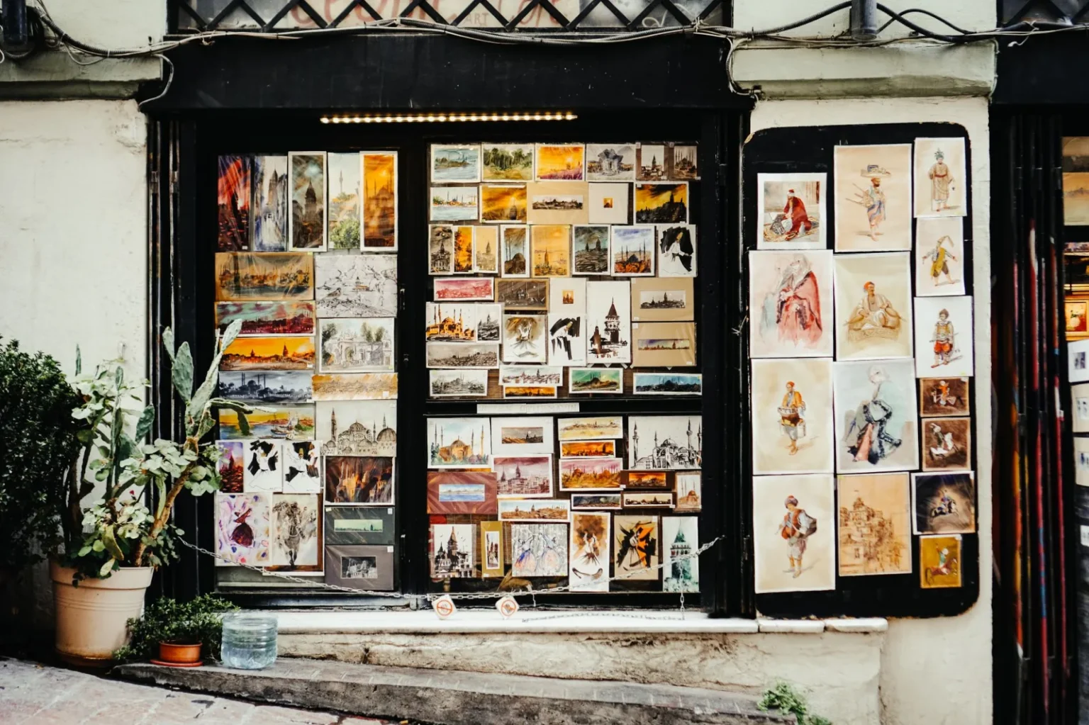 Vibrant art gallery window showcasing diverse paintings and sketches in an urban outdoor street setting.