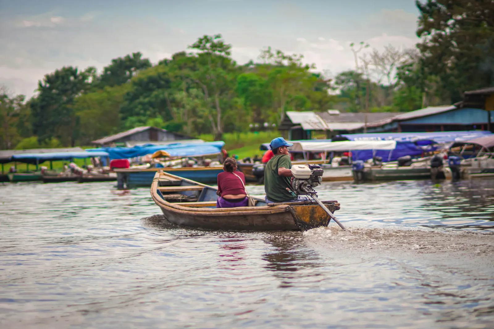 A man and woman navigating a motorboat on the Amazon River near Leticia, Colombia. Vibrant waterway scene.
