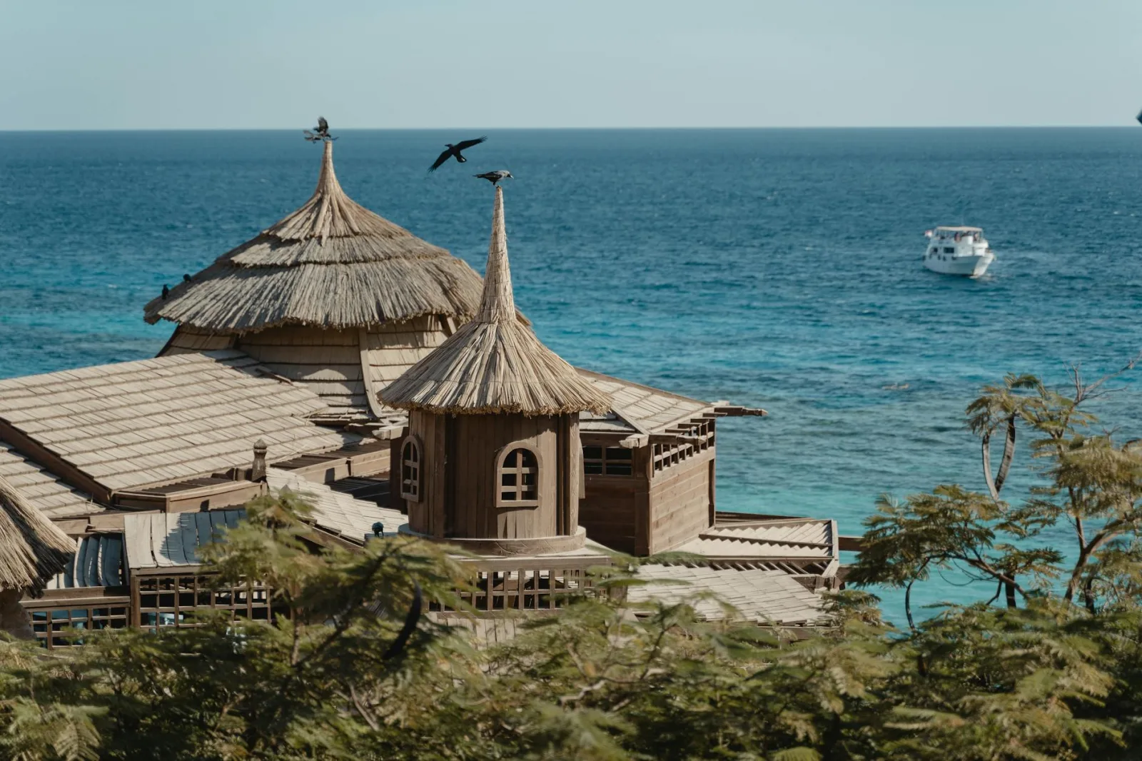 Explore a tranquil coastal resort with unique thatched roofs overlooking the azure sea.