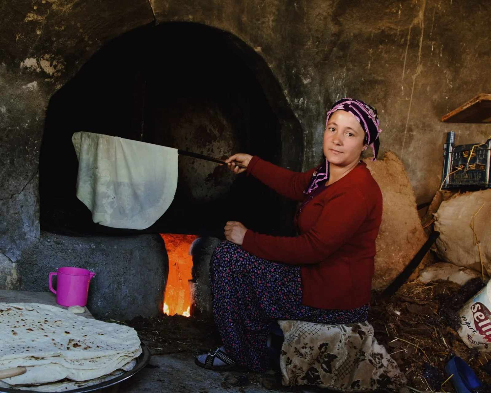A woman baking traditional bread in a wood-fired oven, showcasing artisanal skills.