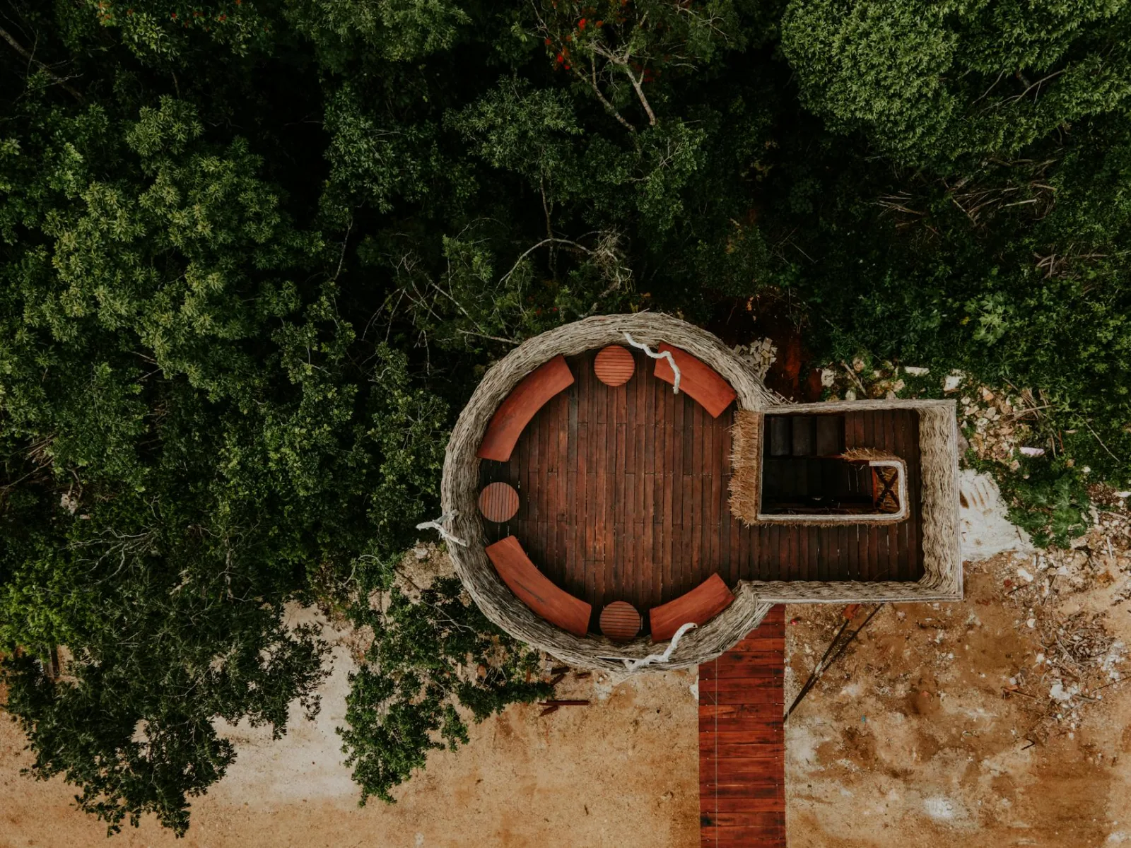 Rustic circular observation deck surrounded by lush greenery, captured from above.