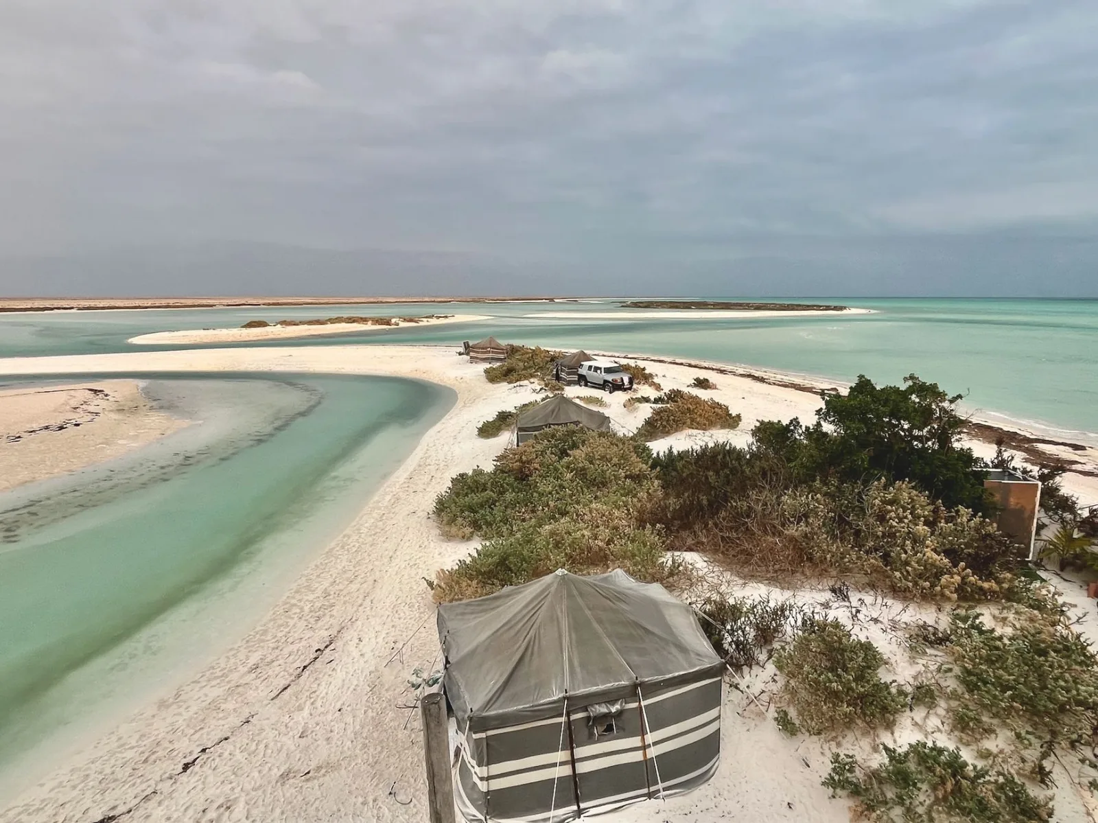 Serene beach with turquoise waters and tents, capturing Oman's natural beauty.