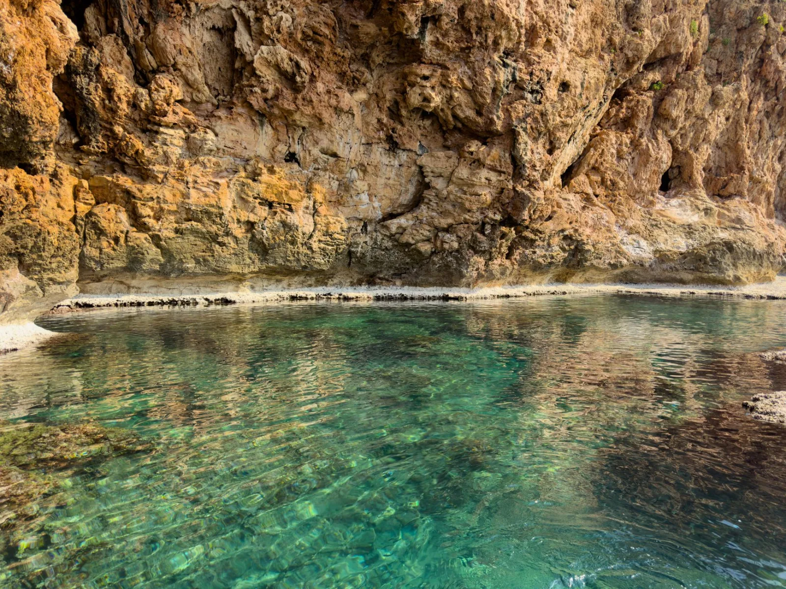 A serene view of clear turquoise water by a rocky cliff, ideal for travel inspiration.