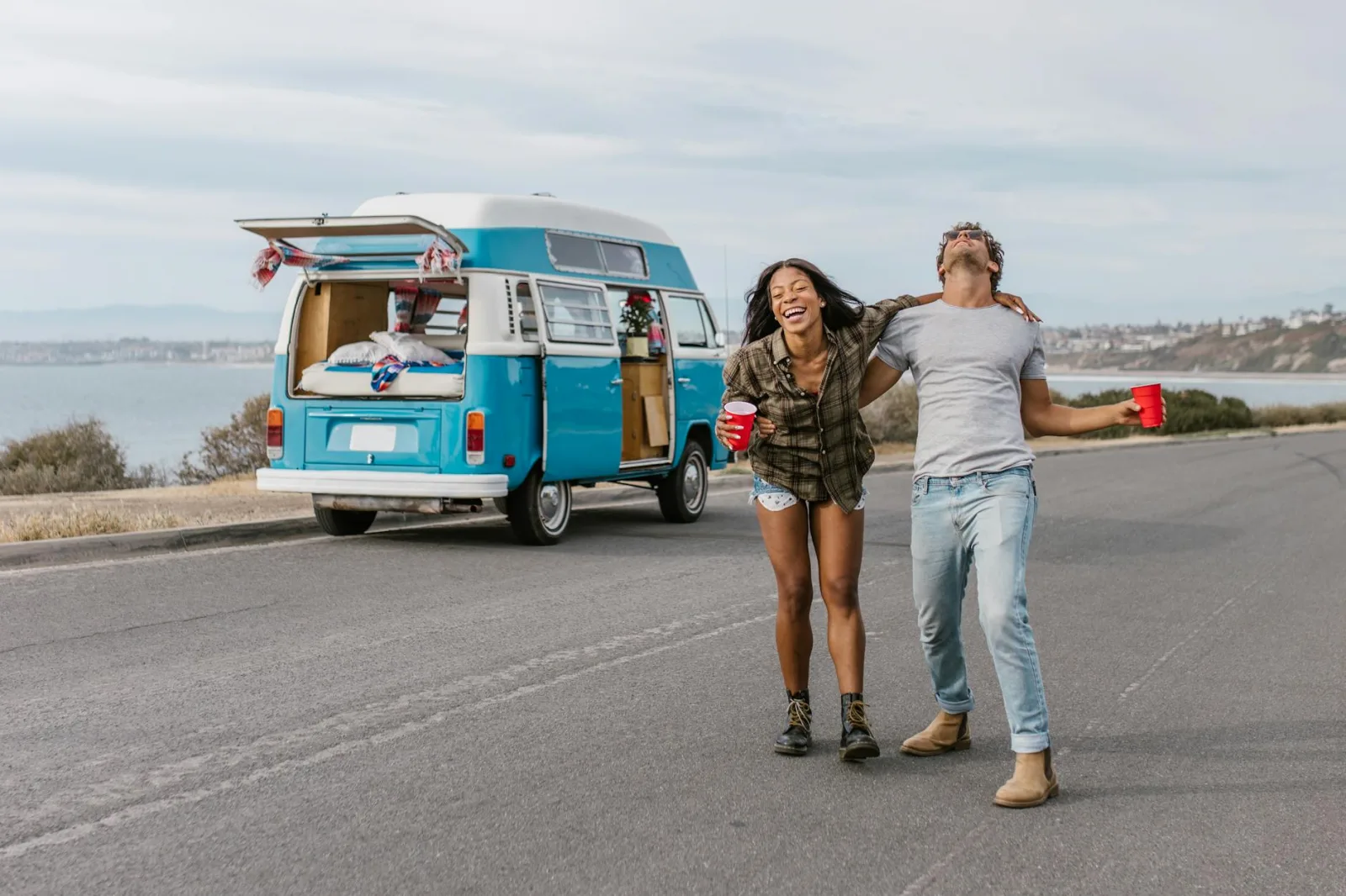 Young couple enjoying a carefree road trip by the seaside with a vintage van.