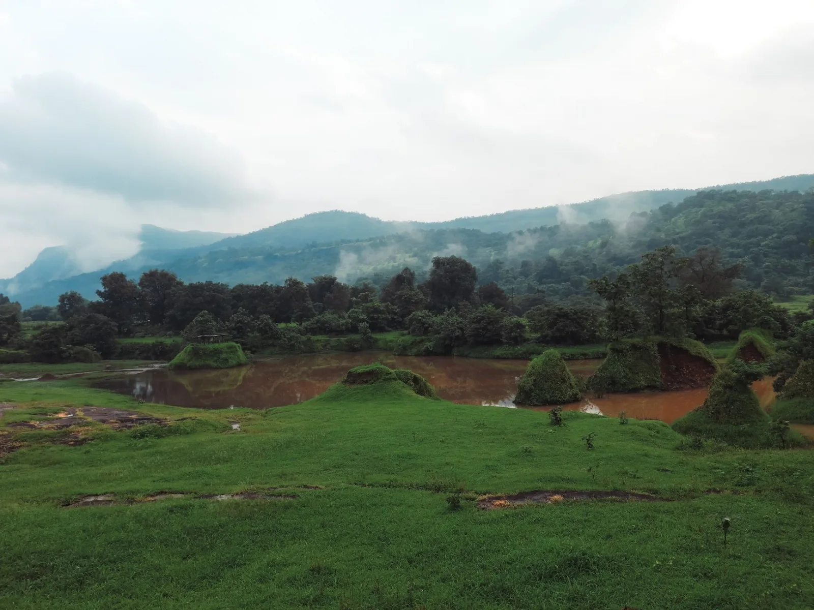 Tranquil view of a misty landscape with lush green hills and a serene lake.