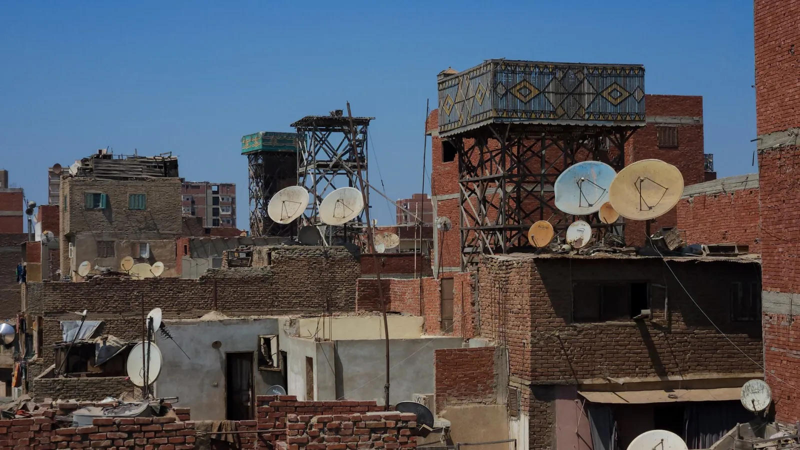 Cairo's rooftops showcase satellite dishes and urban structures under a clear sky.