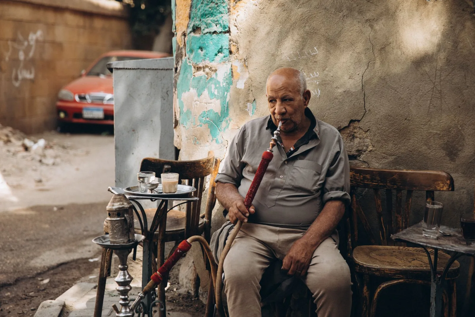 An elderly man sits outdoors enjoying shisha in Cairo, Egypt, reflecting local culture.