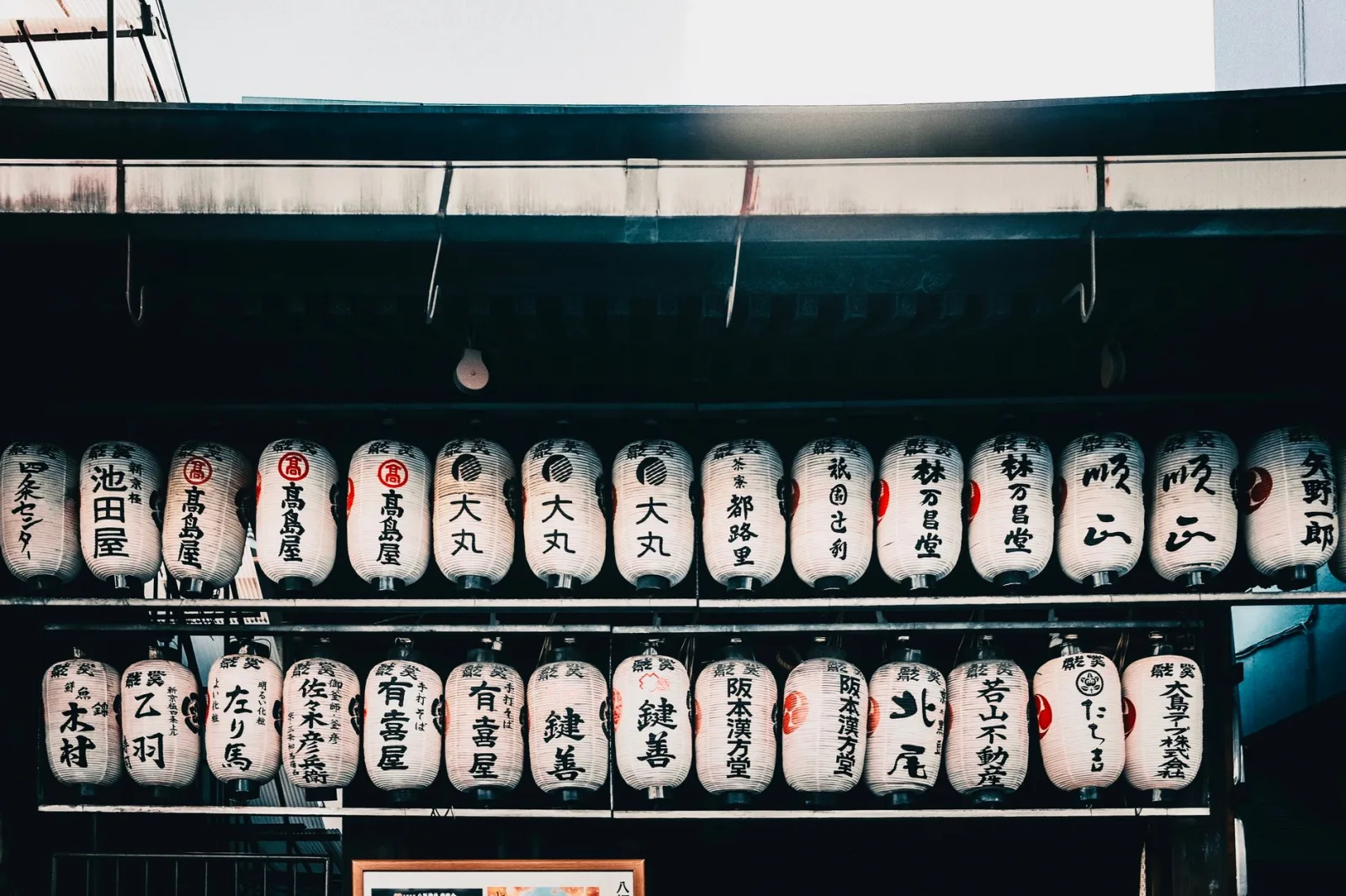 Illuminated Japanese lanterns with kanji characters at a traditional market.