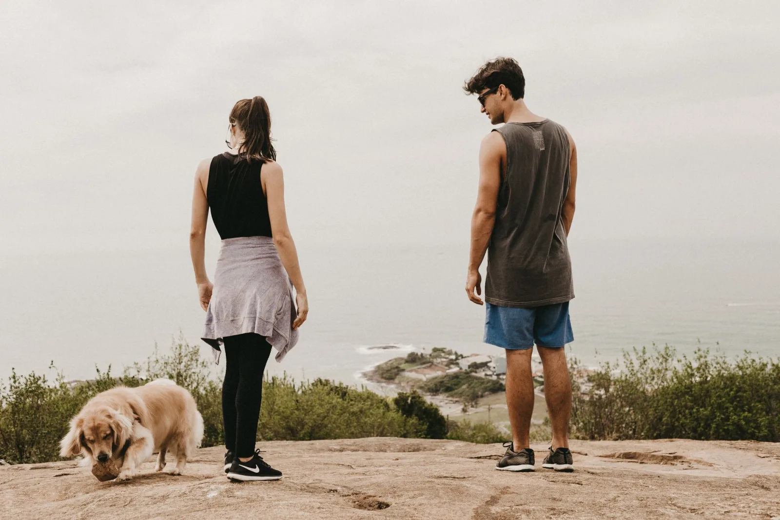 Man and woman with dog enjoying scenic coastal views, casual outdoor adventure.