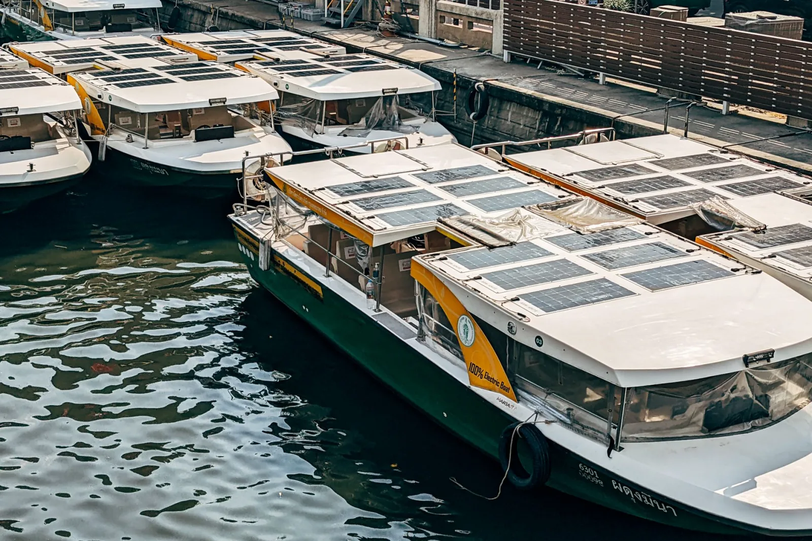 A fleet of solar-powered boats docked at an urban marina, showcasing green transportation.