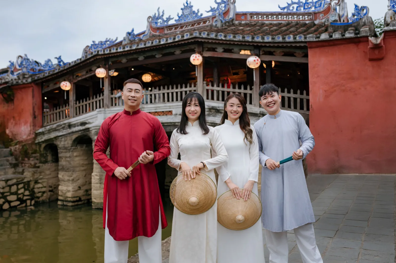Group in traditional Vietnamese attire near Hoi An's historic Japanese Bridge.