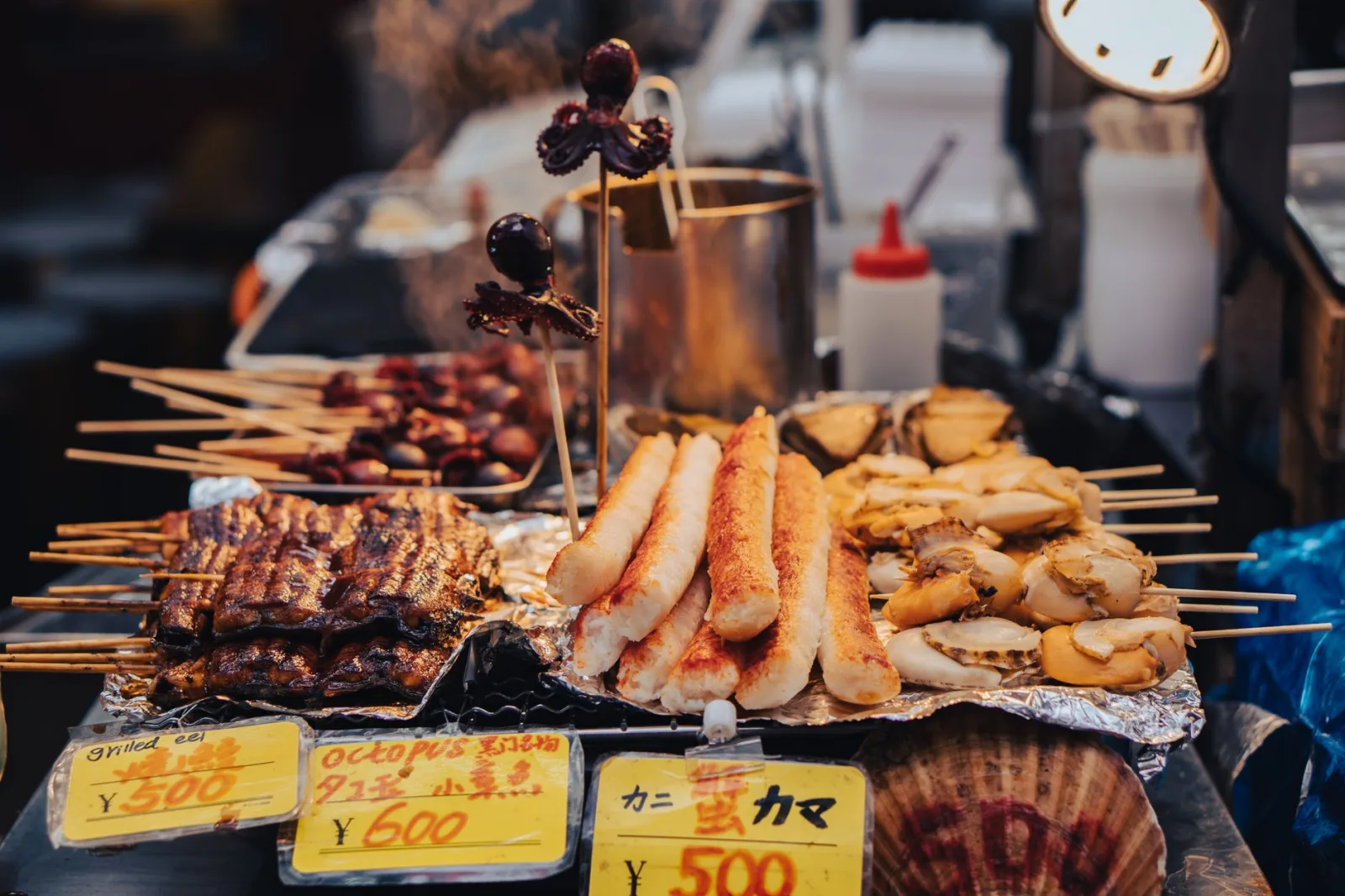 A diverse selection of grilled skewers showcasing delicious Japanese street food at a bustling market stall.
