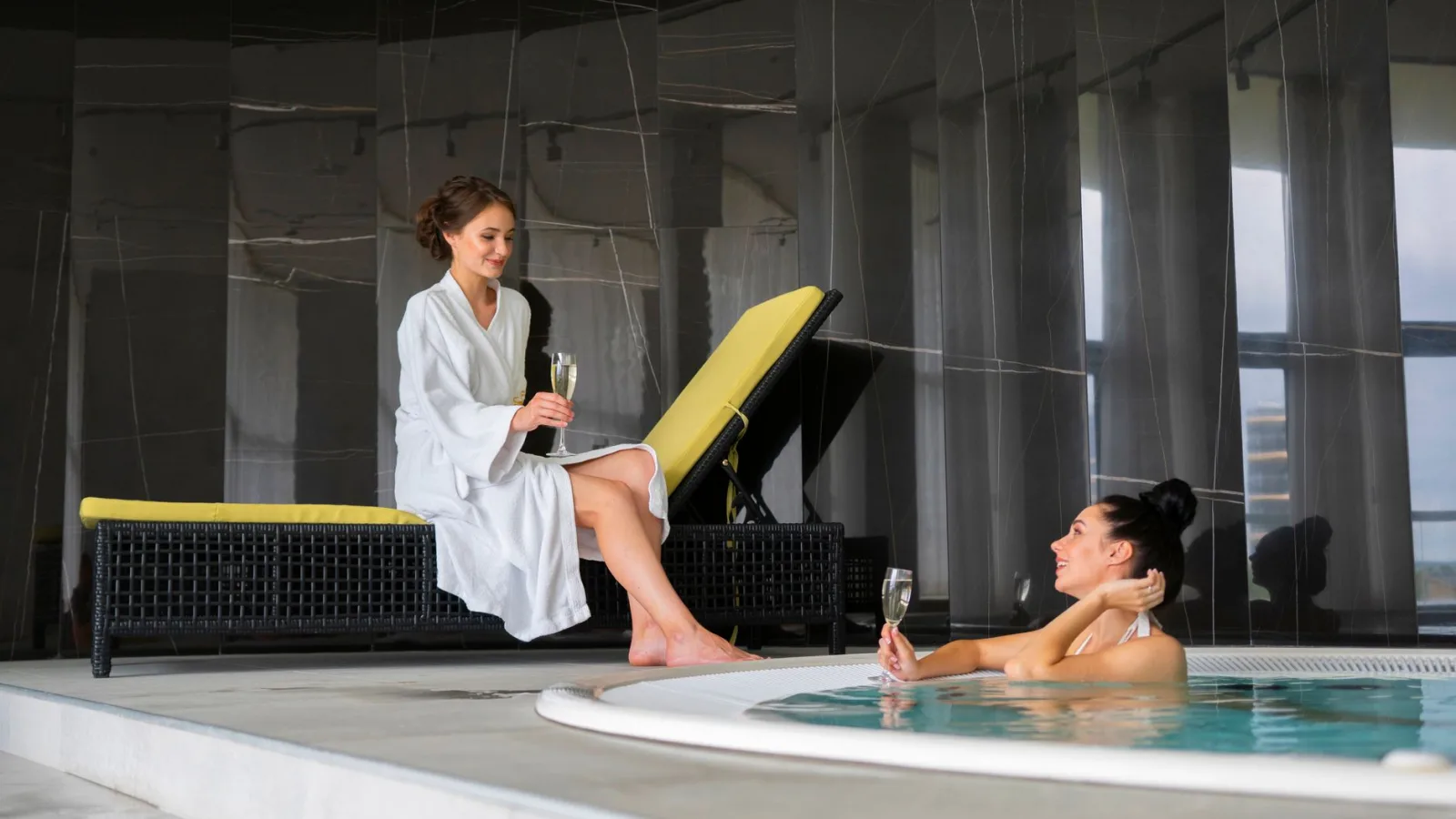 Two women enjoy a luxurious poolside moment with champagne, embodying relaxation and leisure.