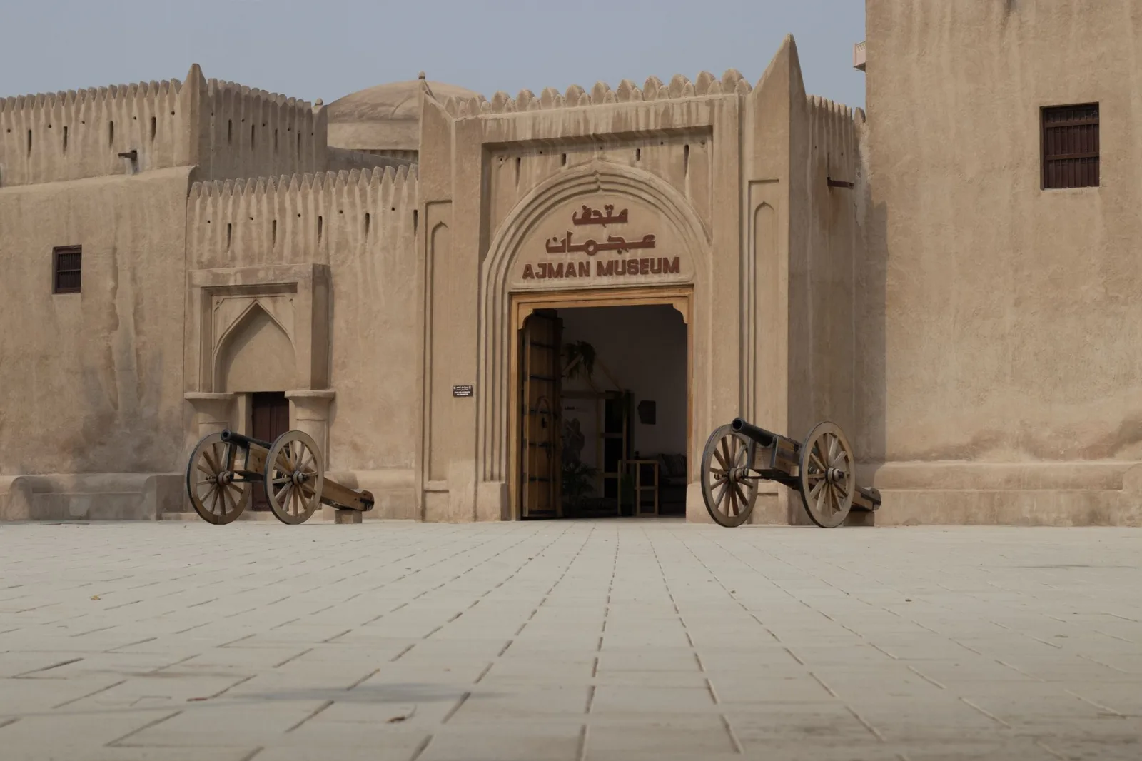 Photograph of Ajman Museum entrance featuring traditional architecture and historic cannons.