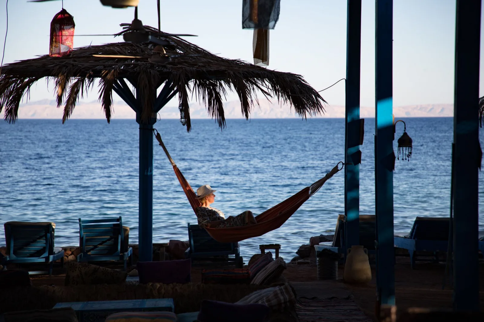 Woman enjoying leisure time in a hammock by the ocean during twilight. Perfect vacation scene.