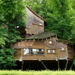 A charming wooden treehouse surrounded by dense green foliage, offering a secluded retreat.