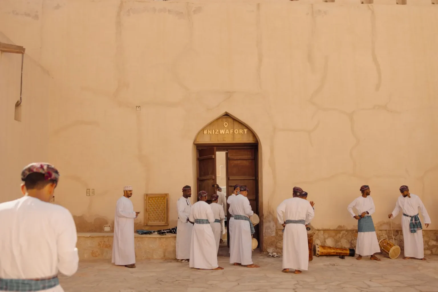 Group of men perform a traditional Omani dance in front of Nizwa Fort, Oman.