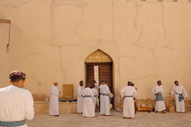 Group of men perform a traditional Omani dance in front of Nizwa Fort, Oman.