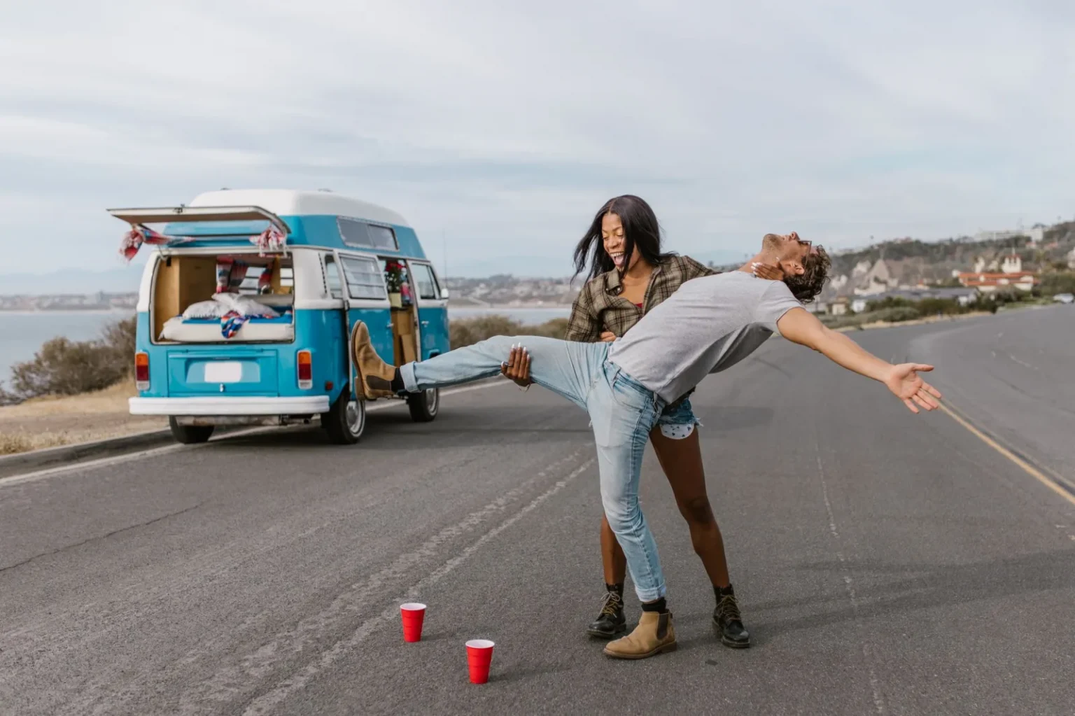 Couple having fun by a van on the road, capturing adventure and joy.