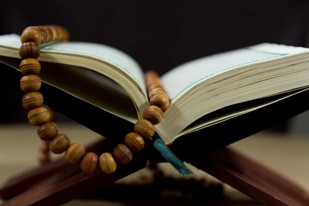 An open Quran with prayer beads on a wooden stand, symbolizing faith and spirituality.