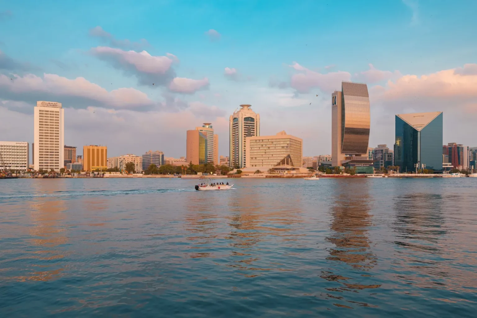 Stunning view of Dubai's skyline and Dubai Creek at sunset with reflecting skyscrapers.