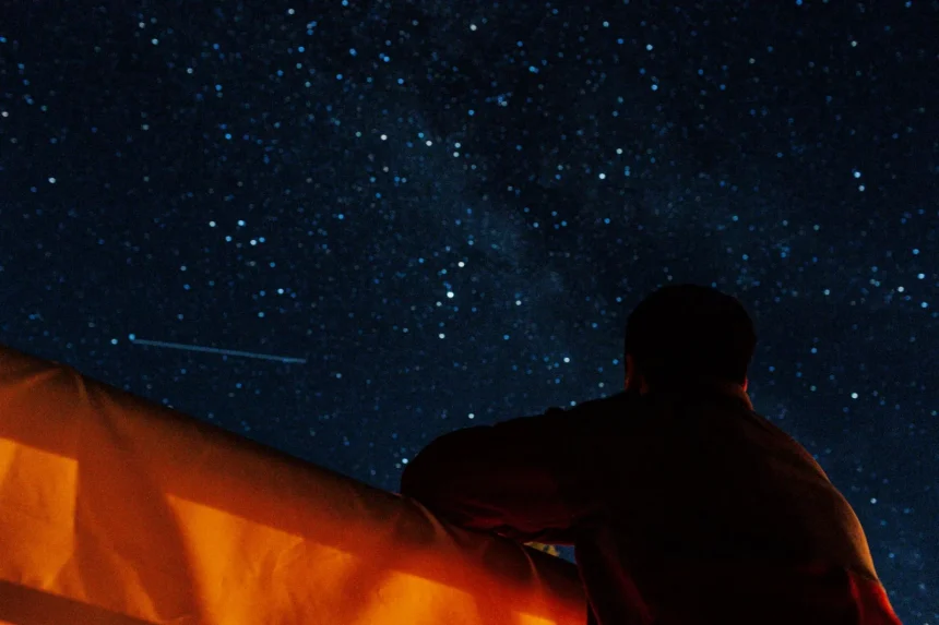 A person enjoys stargazing under a clear, starry night sky, capturing the beauty of the Milky Way.
