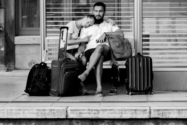 A couple waits with luggage on a platform bench, capturing a moment of travel and companionship.