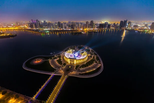 Dramatic aerial view of Al Majaz Island and city skyline in Sharjah at night.