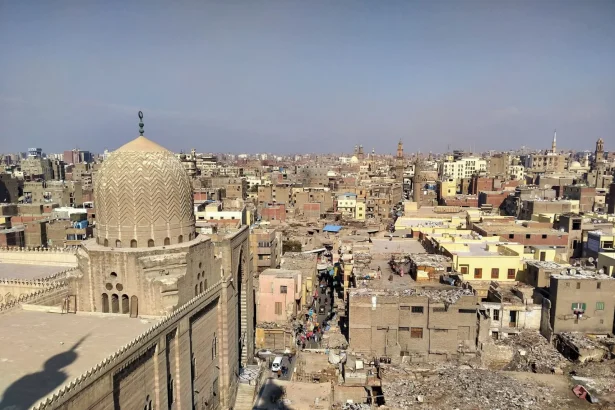 Aerial view of historic Old Cairo showcasing dense residential buildings and a prominent mosque dome under clear skies.