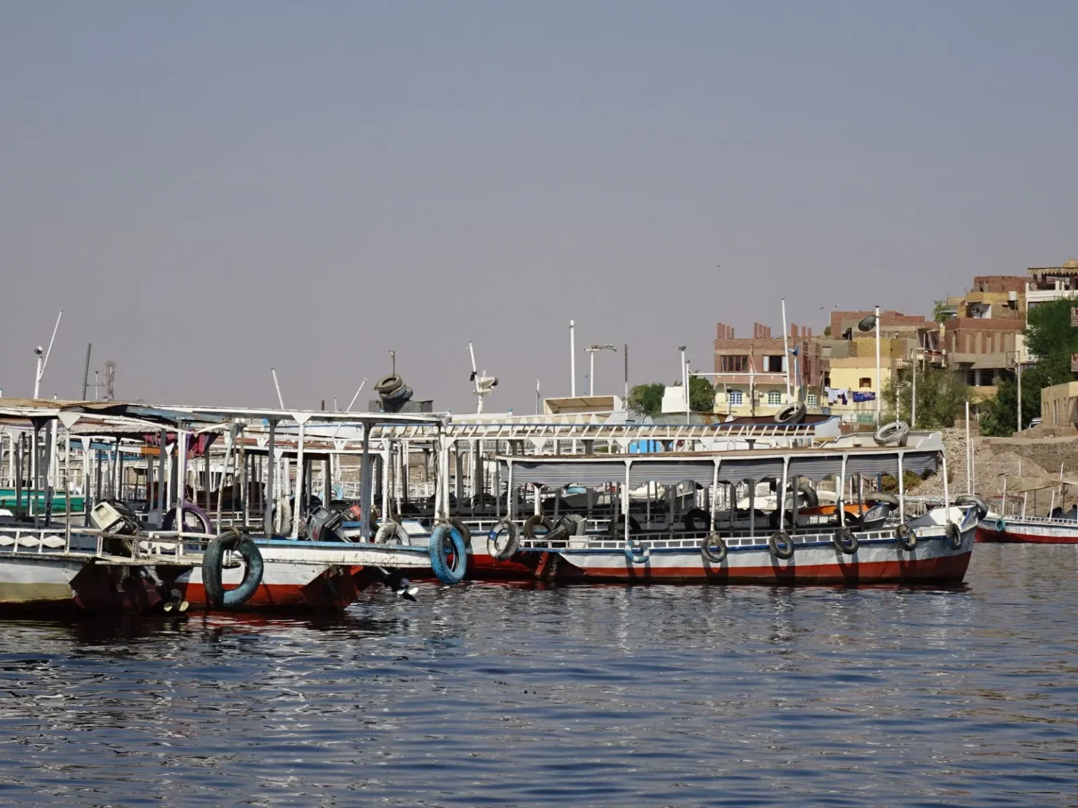 Colorful boats docked along the Nile River in Egypt under a clear blue sky.